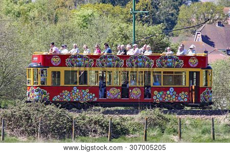 Seaton, Devon, England - May 22nd 2012: A Decorated Red Tram Travels Along The Seaton Tramway On Its