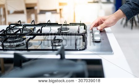 Male Hand Turning Switch Knob On Modern Gas Stove In Kitchen Showroom. Cooking Appliance In Domestic