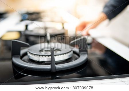 Male Hand Turning Switch Knob On Modern Gas Stove In Kitchen Showroom. Cooking Appliance In Domestic