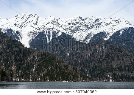 Lake Ritsa In Abkhazia In Spring. The Mountain Tops Are Covered With Snow. The Beginning Of The Tour