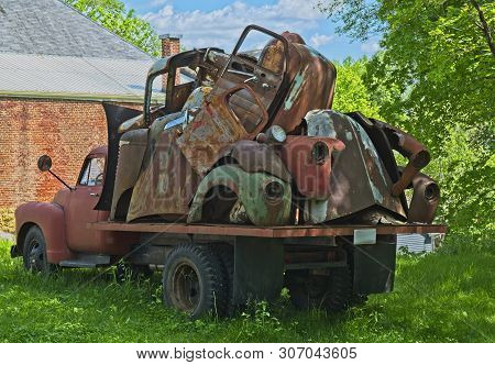 Vintage Truck Hauling Old Rusty Car Parts Piled On The Back Parked In A Empty Lot