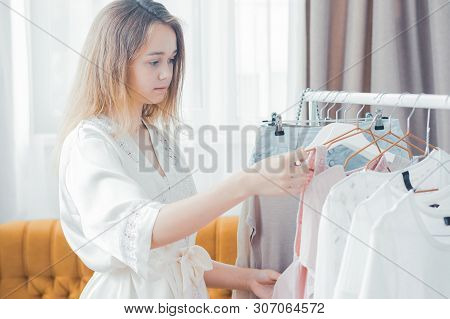 Clothing, Fashion, Style And People Concept - Woman Choosing Clothes At Home Wardrobe