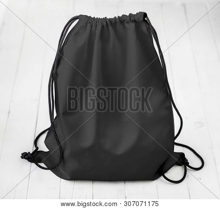 black backpack with strings on planked surface