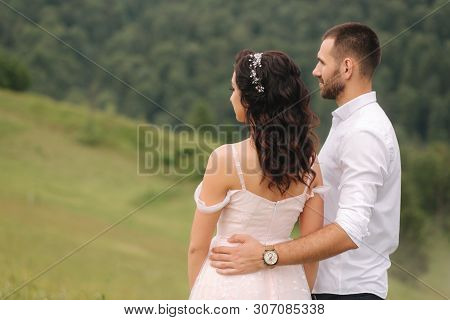 Beautiful Young Wedding Couple Standing On The Green Slope, Hill. Groom And Bride In Carpathian Moun