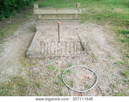 Metal Pole In Horseshoe Pit With Wood Backstop And Plastic Circle