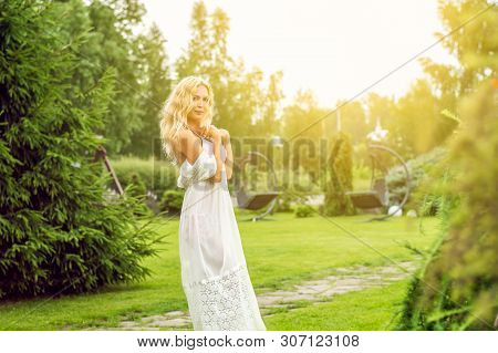 Youmg Beautiful Blond Woman In Beautiful Summer Garden Is Barefoot On Lawn