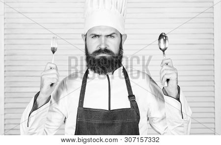 Time To Try Taste. Chef Serious Face Hold Spoon And Fork. Man Handsome With Beard Holds Kitchenware 