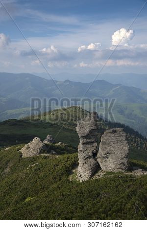 Wonderful Rocks Among Green Mountains. Blue Sky In Background.