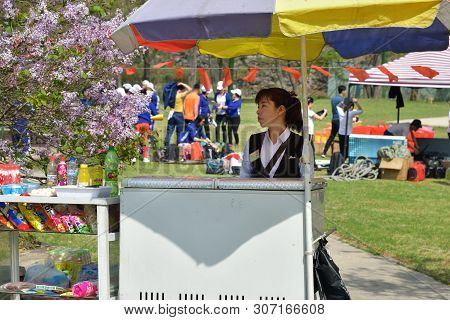 Pyongyang, North Korea - May 1, 2019: Female Seller Of Soda, Chips And Ice Cream Shown In The Taeson