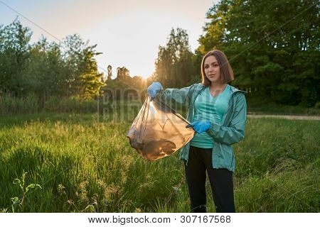 Blogging Concept. The Girl Collects Trash From The Forest In The Trash Bag