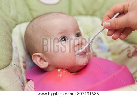 Mother Gives Baby Food From A Baby Spoon. Baby Eating Food First Time. Weaning Baby