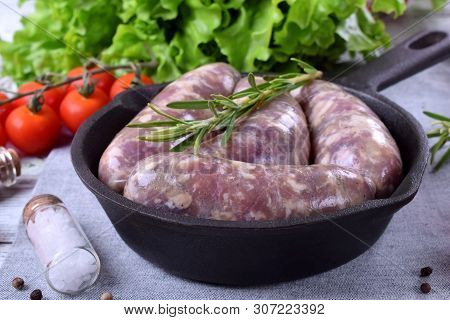 Raw Meat Sausages In A Natural Shell In A Cast Iron Pan Prepared For Grilling