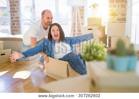Funny and crazy couple having fun riding a cardboad box as a car, smiling happy and lauging at new home