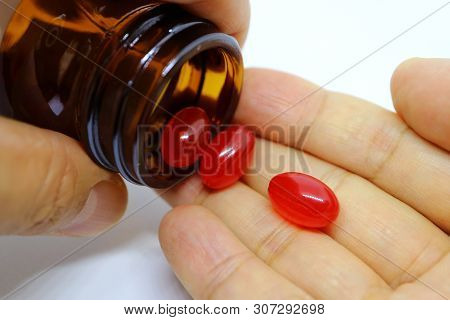 Closeup Of Soft Gel Supplement Pills Spilling From Bottle Into Hand