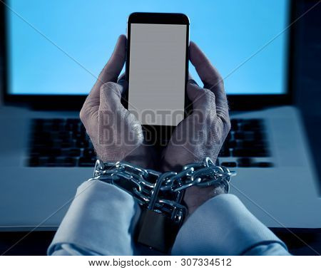Man Hands Tied To Mobile Phone With Chain Padlock In Internet Or Social Media Addiction
