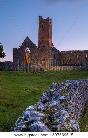 A View Along A Wall Of The Ruins Of The Medieval Quinn Abbey In Quinn, Ireland Against A Deep Blue S
