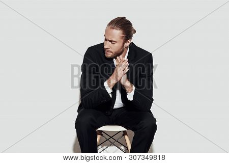 Taking Time To Think. Handsome Young Man In Full Suit Looking Away And Keeping Hands Clasped While S