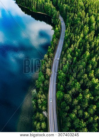 Aerial View Of Road Between Green Forest And Blue Lake In Finland