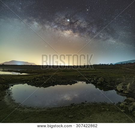 The Stars In The Sky Reflect The Light At Night. The Milky Way Above The Mountains And The Pond Mae