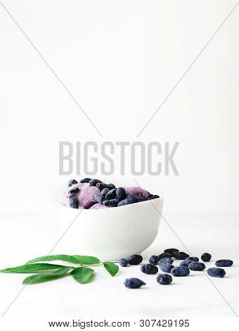 Ice-cream Decorated With Fresh Berries Of A Honeysuckle And Green Leaves On White Background. Close-