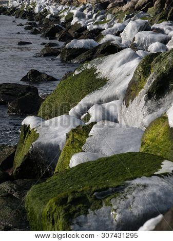 Winter Coast Of The Black Sea. Huge Stones Covered With Green Moss And Ice.