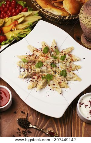 Caucasian Traditional Foodl Dushbere, Gurze Served With Yogurt And Tomato Sauce. In White Plate Deco
