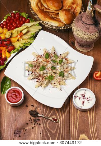 Caucasian Traditional Foodl Dushbere, Gurze Served With Yogurt And Tomato Sauce. In White Plate Deco