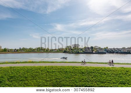 Capelle Aan Den Ijsel, Rotterdam, Netherlands - April 22, 2019 : People Cycling By The Ijsel Canal I