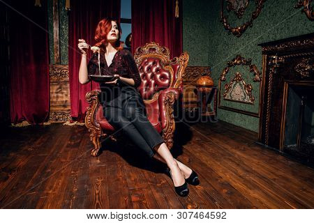 A full length portrait of a beautiful woman posing in the vintage interior and having a meal. Beauty, fashion, interior.