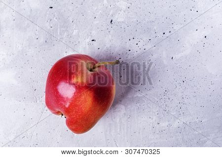 One Ugly Ripe Red  Apple On Grey Concrete Background.