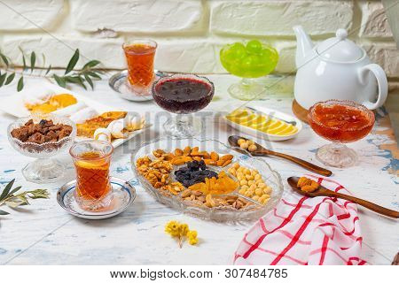 Tea Set With Varieties Of Traditional Nuts, Lemon, Confiture And Sweets Served On White Tablecloth -