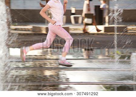 Girl Teenager Happily Rushes Between Spray Of A Fountain In A Summer Sunny Day