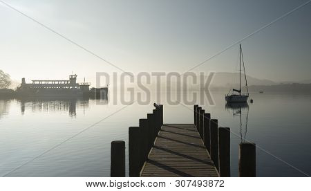 Beautiful Unplugged Landscape Image Of Sailing Yacht Sitting Still In Calm Lake Water In Lake Distri