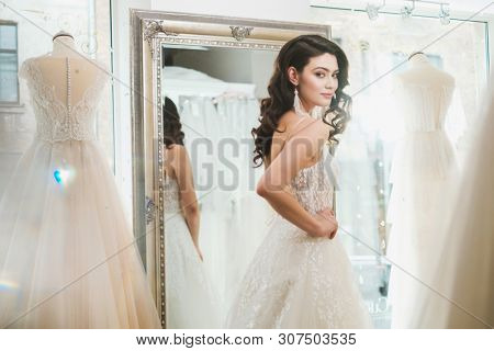 Beautifu bride choosing wedding dress in a wedding salon