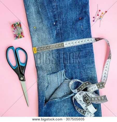 Folded In Half Blue Jeans With Large Hole On Pant Leg, Multi Coloured Headed Sewing Pins, White Tail