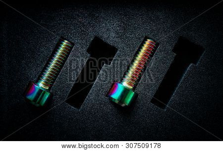 Colorful Metal Titan Screw Bolts On A Black Pad. Workforce Absence, Bad Teamwork Concept.
