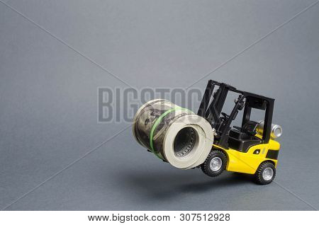 A Yellow Loader Stands On The Rear Wheels Holding A Big Bundle Of Dollars. Concept Of Attracting Inv