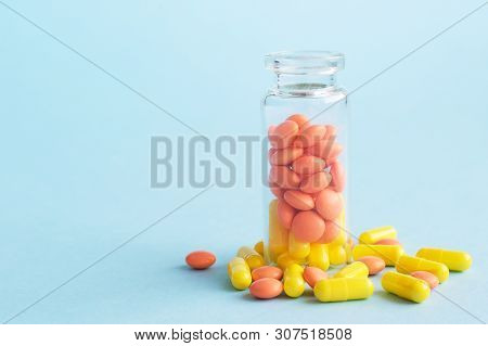 Yellow And Orange Capsules From Glass Bottle On Blue Background. Copyspace For Text. Epidemic, Paink