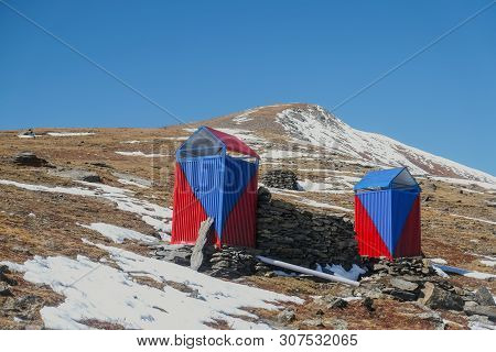 Local Simple Blue And Red Color Restroom. Sanitary Toilet Cabin In The Snow Covered Mountain In Paki