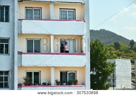 Wonsan, North Korea - May 3, 2019: A Girl On The Loggia Of A Typical Apartment Building In Wonsan. A