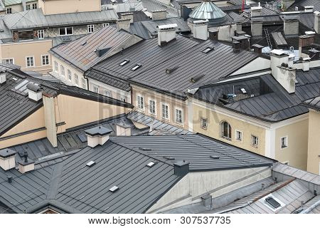 Top View Of Different Buildings Roofs With Chimneys In Typical European City