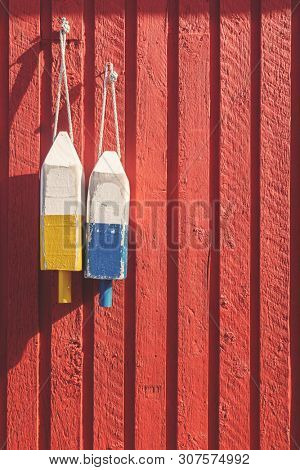 Fishing buoys, used to mark where the lobster pots are dropped, hanging on a red wooden wall in Prince Edward Island, Canada. Spcae for your text.