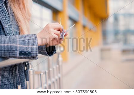 Young Woman Playing Origami Birds, White Cranes In Hands Against Sky Reflection In A Window