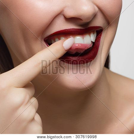 Close-up Portrait Of The Lower Half Of A Woman's Face With A Malicious Grin. He Picks A Long Fingern