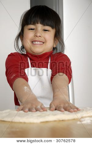 Bambina cucinare una pizza in una cucina.Ragazzino in una cucina.