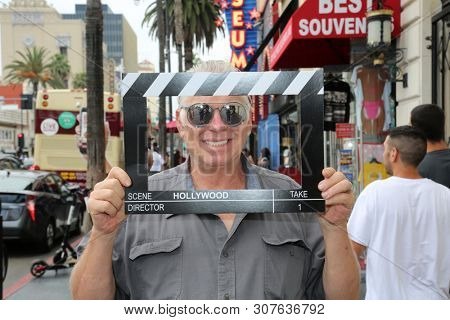 6-18-2019 Hollywood, California: A man wears silver reflective sunglasses while posing with a Hollywood Movie Click Board while on the streets on Hollywood California. Editorial Use Only. 