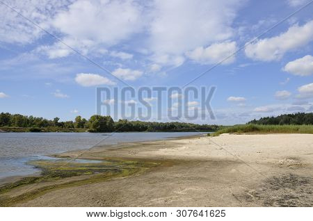 Wide Blue River Is Slow Flowing. Summer. Sunny Weather And White Sand. Green Trees Far Away