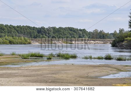 Wide Blue River Is Slow Flowing. Summer. Sunny Weather And White Sand. Green Trees Far Away