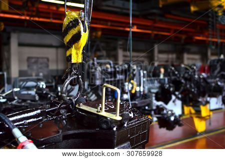 Bridge Lifting Crane Hook Against The Background Of The Assembly Line Industrial Factory. The Concep