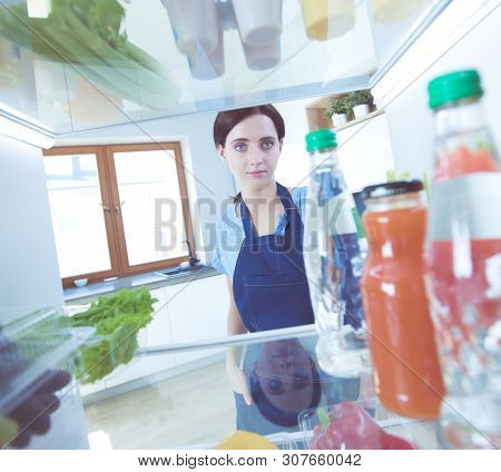 Portrait Of Female Standing Near Open Fridge Full Of Healthy Food, Vegetables And Fruits. Portrait O